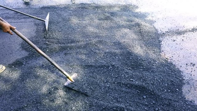 Road worker making road use shovel for swab asphalt for working.