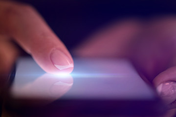 Finger touching phone with dark background with copyspace