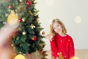 little girl decorating christmas tree