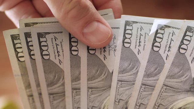 Male hands holding us dollar bills.