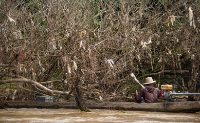A fisherman in the middle of plastic trash at the riverbank of the Dokhtawady River near Hsipaw, Myanmar, south-east Asia.
