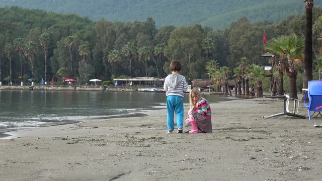 Akyaka, Mugla, Turkey - 12th of November 2019: 4K Boy and girl gather findings on the beach after storm