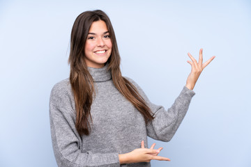 Teenager Brazilian girl over isolated blue background extending hands to the side for inviting to come