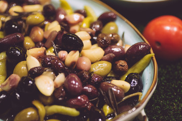 Olives and peppers marinated in oil. Pickled olives in a bowl on the table. Vegetarian snack