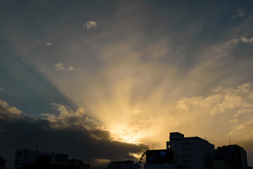 夕暮れの空に輝く薄明光線と街のシルエット