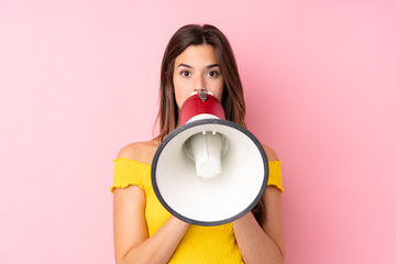 Teenager Brazilian girl over isolated pink background shouting through a megaphone