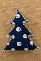 Handmade polka dot textile fabric naive retro style Christmas tree ornament decorated with beads on burlap background