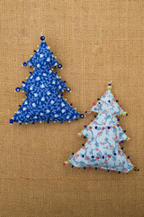 2 handmade blue textile cotton fabric naive retro style Christmas tree ornament decorated with beads on burlap background