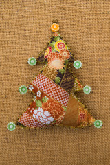 Handmade orange brown  textile cotton fabric naive retro style Christmas tree ornament decorated with beads on burlap background