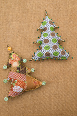 Handmade green pattern and orange brown textile cotton fabric naive retro style Christmas tree ornament decorated with beads on burlap background