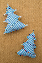 2 Handmade blue striped  textile cotton fabric naive retro style Christmas tree ornament decorated with beads on burlap background