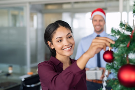 Businesswoman decorating christmas tree at office
