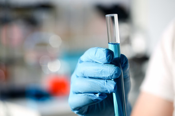 A male chemist holds test tube of glass