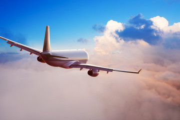 Passengers commercial airplane flying above clouds in sunset light. Concept of fast travel,...