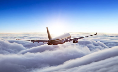 Passengers commercial airplane flying above clouds in sunset light. Concept of fast travel, holidays and business.