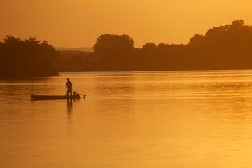 Fototapeta na wymiar Silhouette of the fisherman on the boat during sunset on the Soderica Lake, Croatia