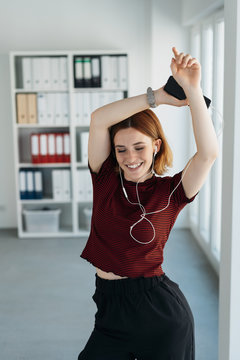 Happy young businesswoman dancing to music