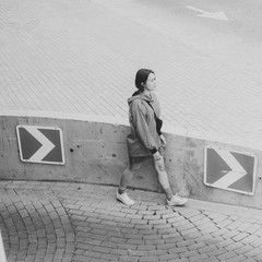 Black and white shot of Young adult female walking on parking