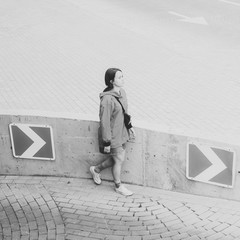 Black and white shot of Young adult female walking on parking