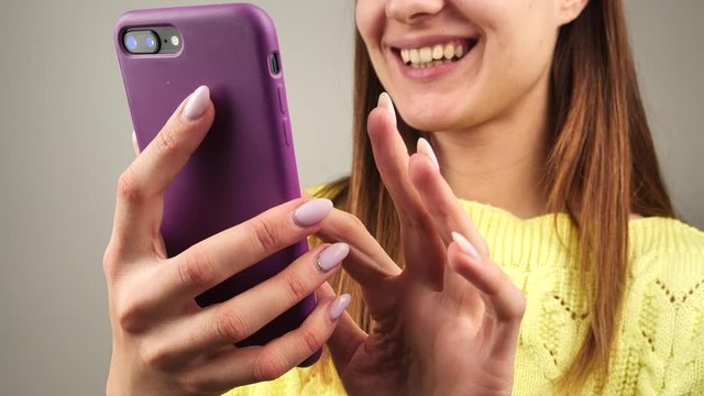 woman communicates on skype via smartphone. She is wearing a bright yellow sweater