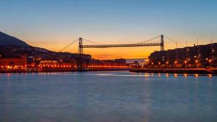 Fototapeta premium Panorama of Portugalete and Getxo with Hanging Bridge of Bizkaia at dusk from La Benedicta pier, Basque Country, Spain 