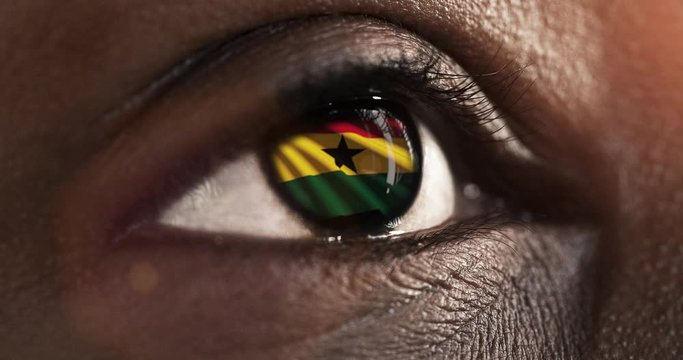 Woman black eye in close up with the flag of Ghana in iris with wind motion. video concept