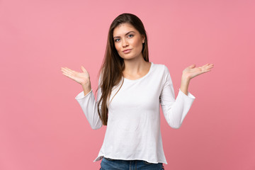 Young woman over isolated pink background having doubts while raising hands