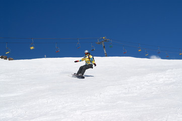 Fototapeta na wymiar Snowboarder descends on snowy ski slope at winter