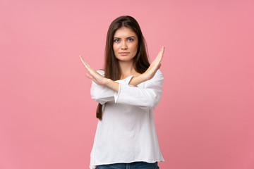 Young woman over isolated pink background making NO gesture