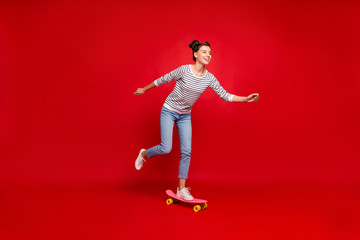 Fototapeta na wymiar Full length profile side photo of positive cheerful girl ride have autumn free time ride her skateboard wear white outfit sneakers isolated over red color background