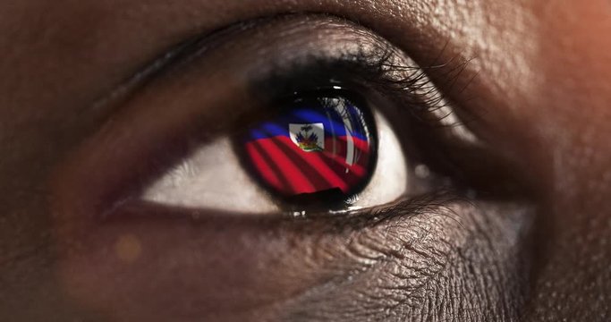 Woman black eye in close up with the flag of haiti in iris with wind motion. video concept