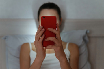Young female browsing with smartphone late at night. Focused on cellphone. Intermet and social network dependence concept