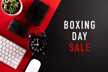 Boxing day Sale text with Alarm clock, keyboard mouse, gift box on red and black background. Online Shopping concept and Boxing day composition.
