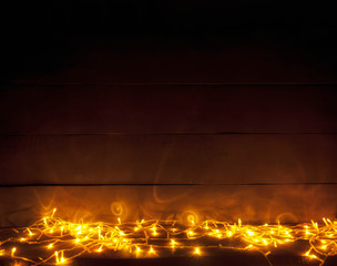 The beautiful blurred christmas background with a lot of yellow lights on the wooden desk