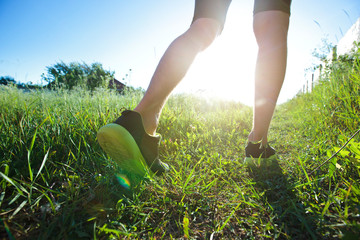 One young man is jogging cross-country through the pathway in the meadow