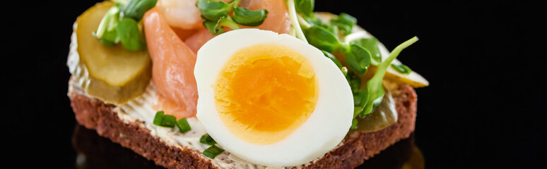 panoramic shot of boiled egg on danish smorrebrod on black