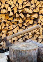 Axe in a stump near the stack of firewood