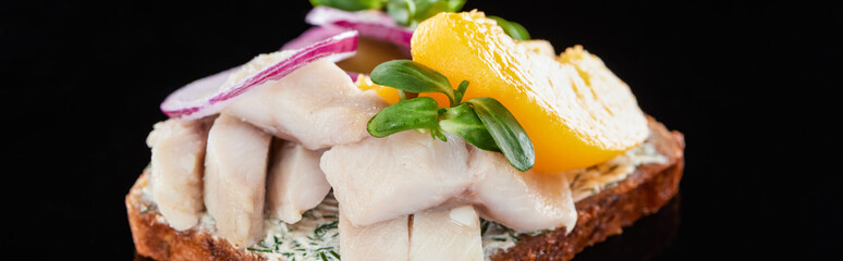 panoramic shot of herring fish and canned peaches on fresh smorrebrod sandwich on black