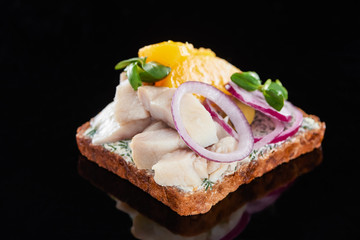 close up of herring fish on prepared danish smorrebrod sandwich on black