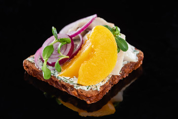 close up of herring fish on delicious smorrebrod sandwich on black