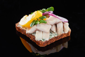 close up of herring fish on delicious smorrebrod sandwich on black