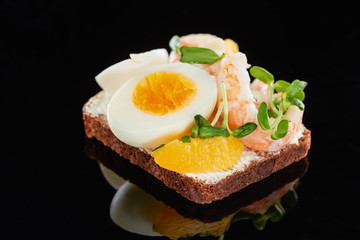 close up of rye bread with tasty shrimps on smorrebrod sandwich on black