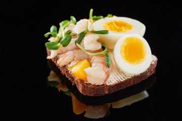 close up of rye bread with delicious shrimps on smorrebrod sandwich on black