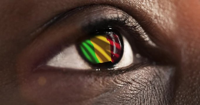 Woman black eye in close up with the flag of Mali in iris with wind motion. video concept