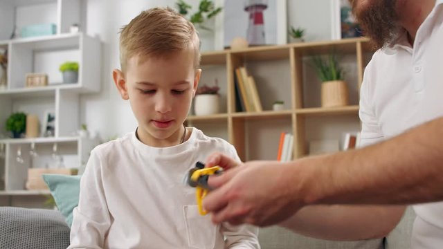 Father and son play with the constructor in the living room