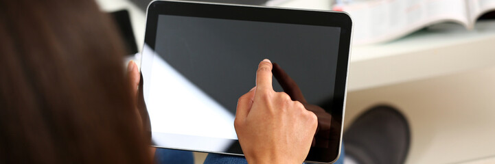 female hand holds tablet in home setting while