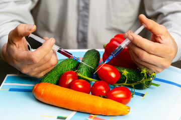 Chemical processing of vegetables, fertilizers and GMOs A man injects chemicals into a tomato GMO...