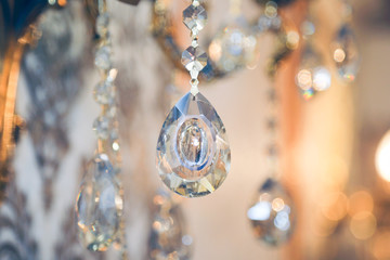 The glass pendant on the wall lamp shines in the sun. A crystal product for decorating sconces and fixtures