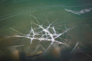 Texture of frozen and split ice on the lake. Turquoise ice on the lake froze on triangular breakwaters