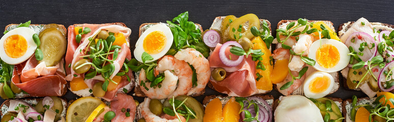 panoramic shot of traditional smorrebrod sandwiches with boiled eggs on grey surface